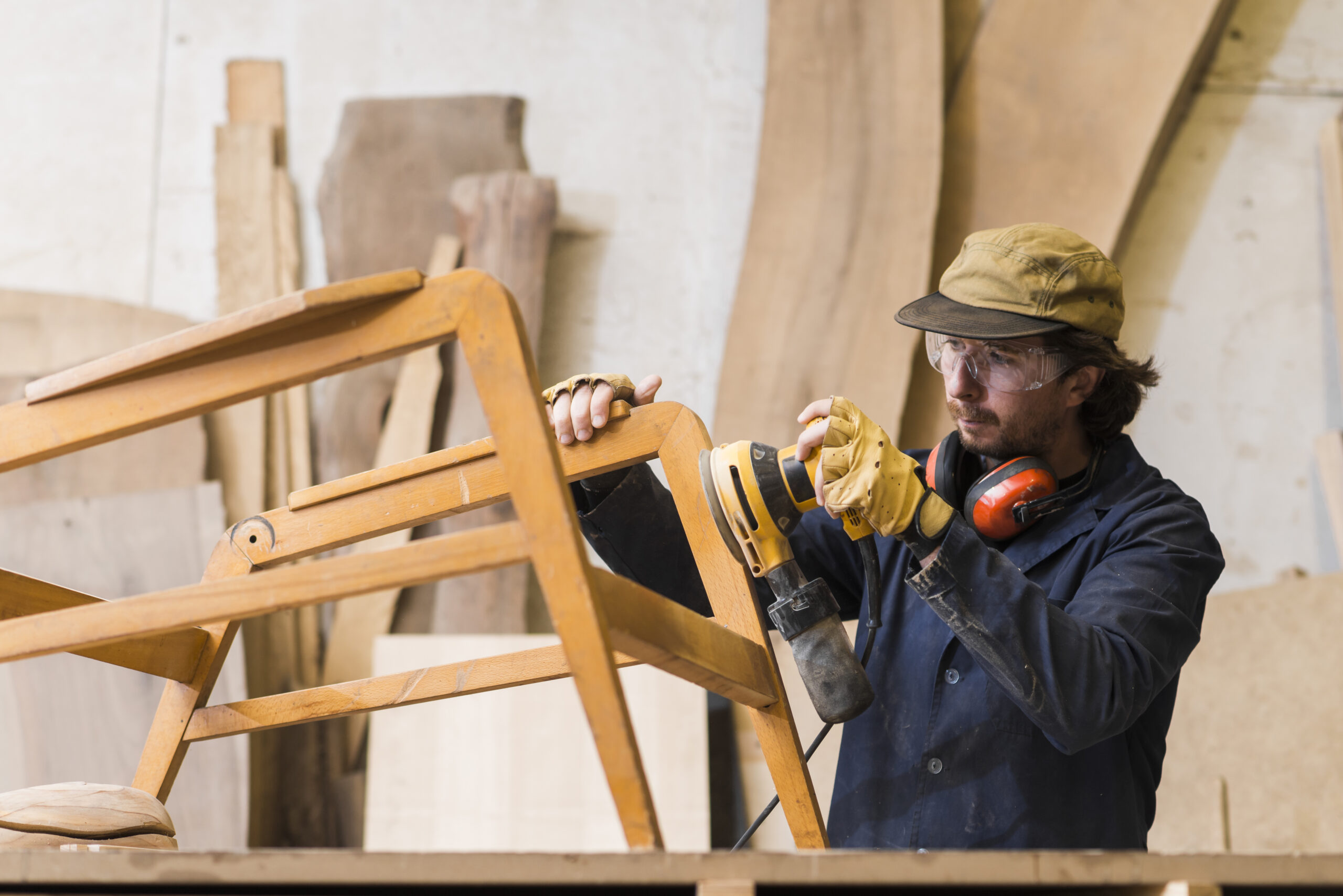 homme charpentier poncant un bois avec une ponceuse orbitale dans un atelier
